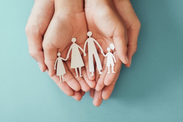 Hands holding a paper family.