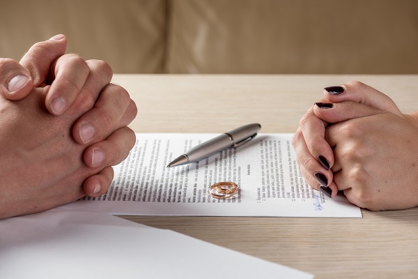 Hands of wife and husband signing divorce documents